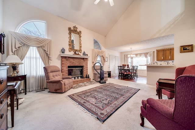 carpeted living room with ceiling fan with notable chandelier, a fireplace, and high vaulted ceiling