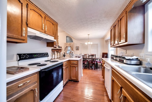 kitchen featuring pendant lighting, white appliances, an inviting chandelier, dark hardwood / wood-style floors, and a textured ceiling