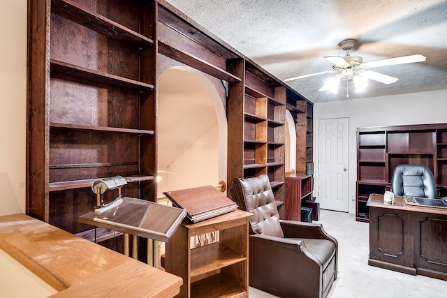 office featuring a textured ceiling, light colored carpet, and ceiling fan