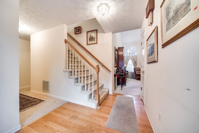 foyer with a textured ceiling and light hardwood / wood-style flooring