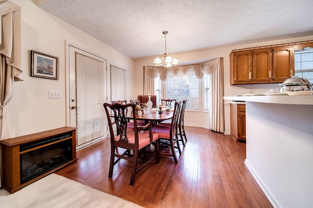 dining space with hardwood / wood-style flooring, a notable chandelier, and a textured ceiling