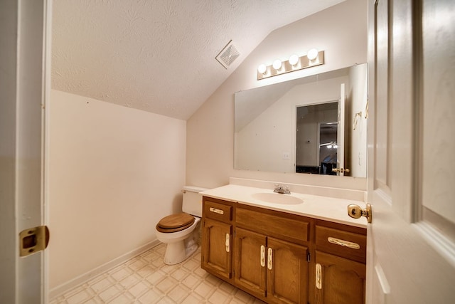 bathroom with a textured ceiling, vanity, lofted ceiling, and toilet