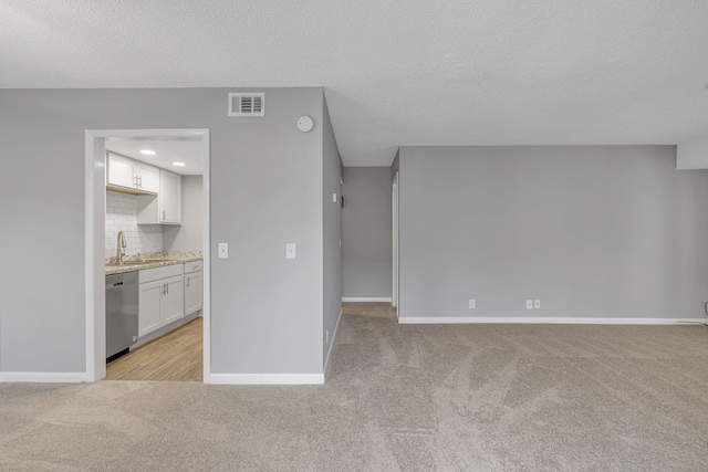 unfurnished living room with light carpet, sink, and a textured ceiling