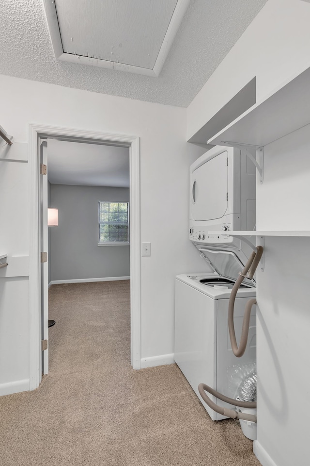 laundry area featuring a textured ceiling, light colored carpet, and stacked washer / drying machine