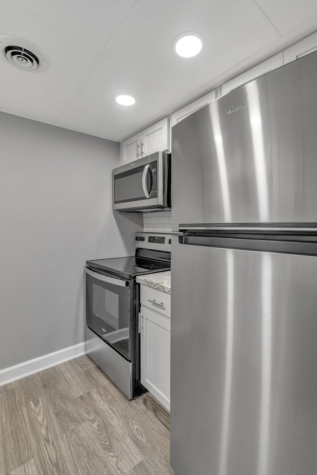 kitchen featuring decorative backsplash, light stone counters, stainless steel appliances, light hardwood / wood-style flooring, and white cabinets