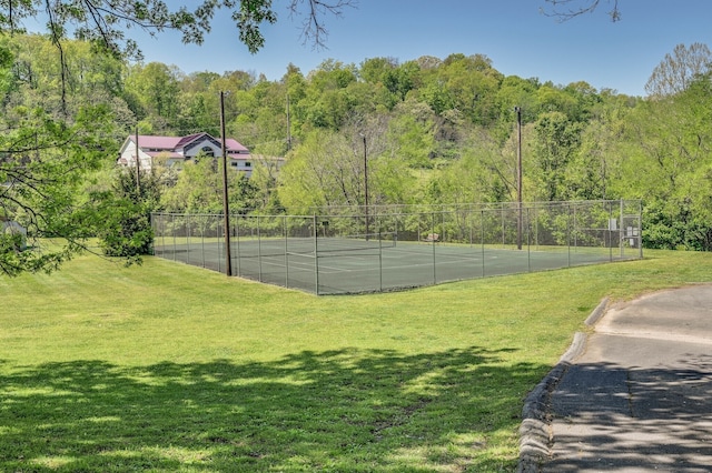 view of tennis court featuring a yard