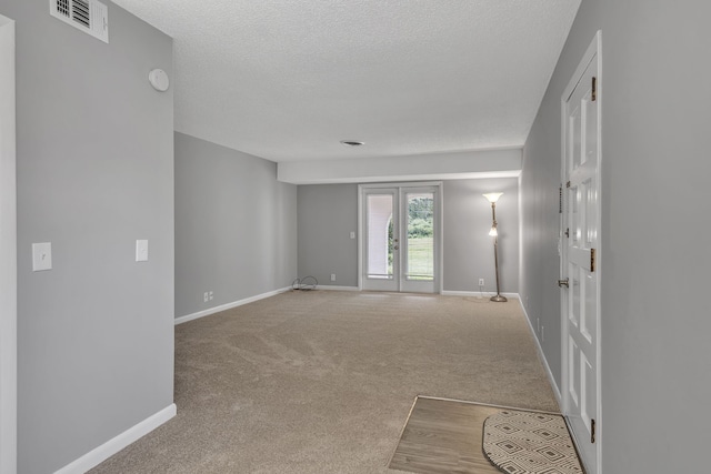 carpeted empty room featuring a textured ceiling