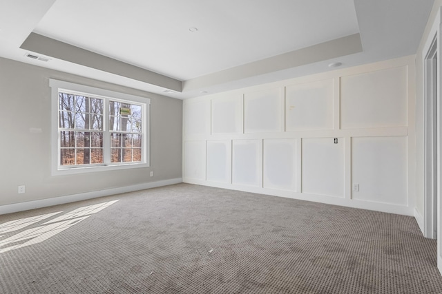 unfurnished bedroom with visible vents, a decorative wall, and a tray ceiling