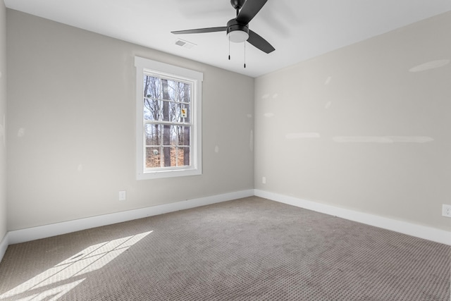 carpeted spare room featuring visible vents, baseboards, and a ceiling fan