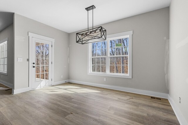 unfurnished dining area featuring visible vents, baseboards, and wood finished floors