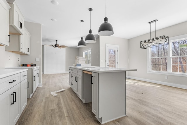 kitchen with light countertops, a ceiling fan, light wood-type flooring, and a center island