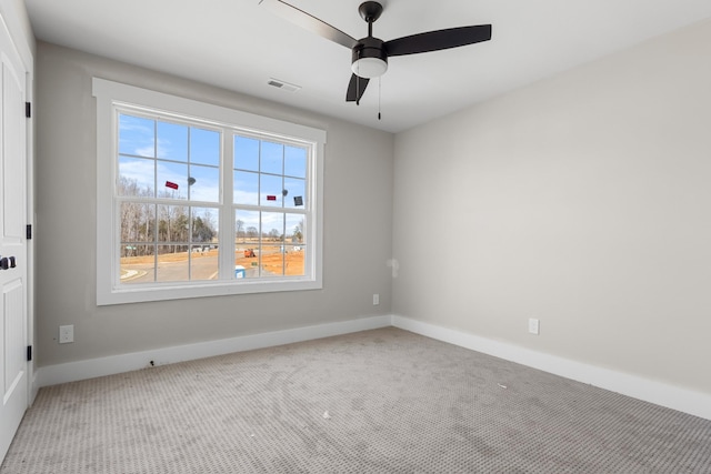 carpeted empty room with baseboards, visible vents, and ceiling fan