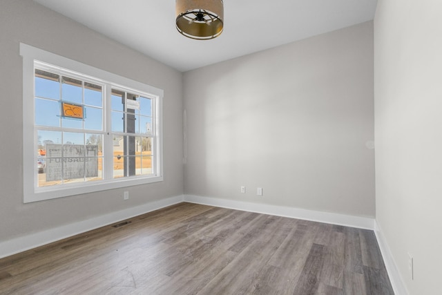 spare room featuring visible vents, baseboards, and wood finished floors