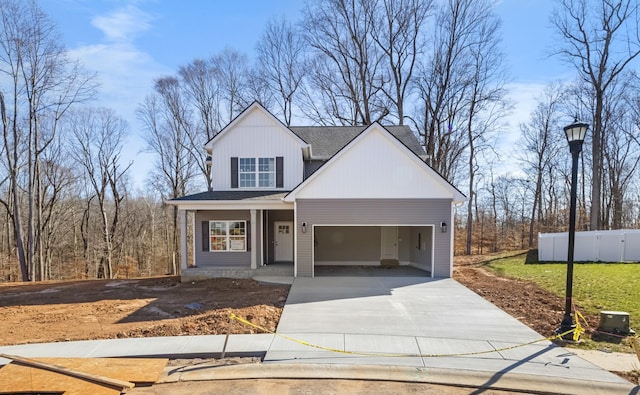 view of front of house featuring a garage, concrete driveway, and fence