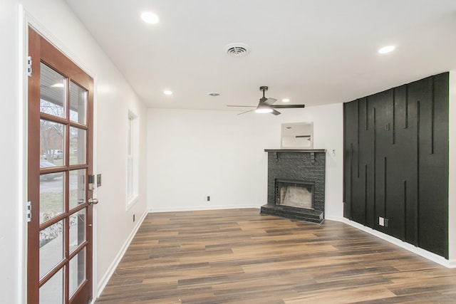 unfurnished living room with a fireplace, ceiling fan, and dark wood-type flooring