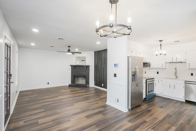 kitchen featuring sink, hanging light fixtures, stainless steel appliances, dark hardwood / wood-style flooring, and white cabinets