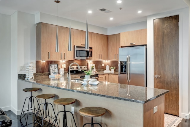 kitchen featuring backsplash, hanging light fixtures, stone countertops, kitchen peninsula, and stainless steel appliances