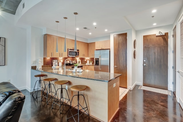 kitchen featuring stone countertops, decorative backsplash, decorative light fixtures, kitchen peninsula, and stainless steel appliances