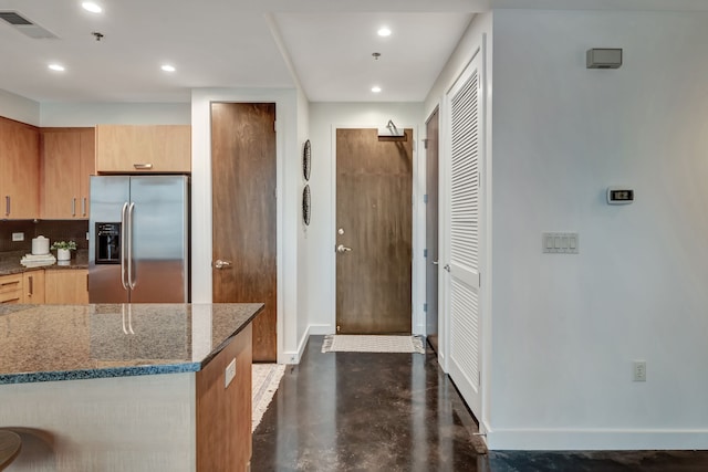 kitchen featuring stainless steel fridge, dark stone counters, and tasteful backsplash