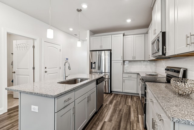 kitchen featuring sink, stainless steel appliances, dark hardwood / wood-style floors, pendant lighting, and a center island with sink