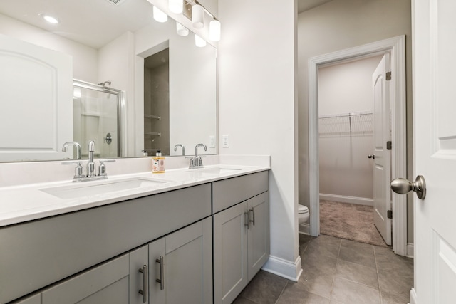 bathroom with tile patterned floors, vanity, toilet, and a shower with shower door