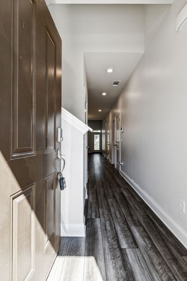 corridor with dark wood-type flooring and a wall unit AC