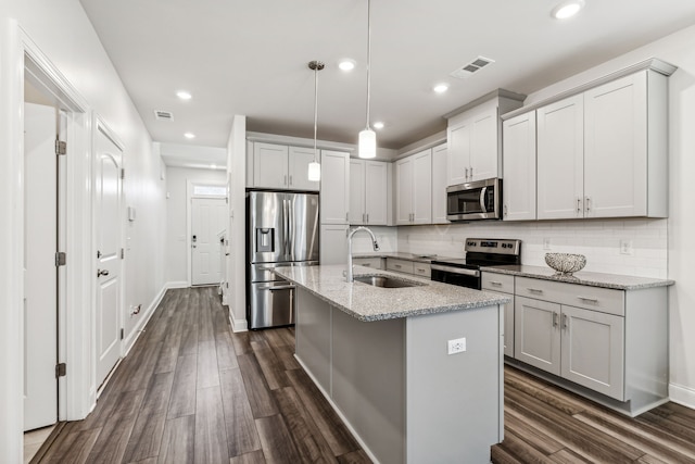 kitchen with light stone countertops, sink, hanging light fixtures, stainless steel appliances, and dark hardwood / wood-style floors