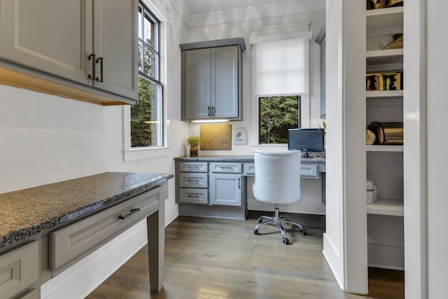 home office with wood-type flooring and built in desk