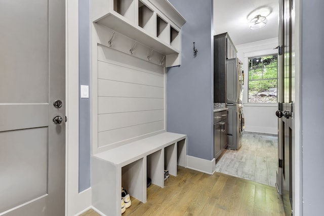 mudroom featuring stacked washer / dryer and light hardwood / wood-style flooring