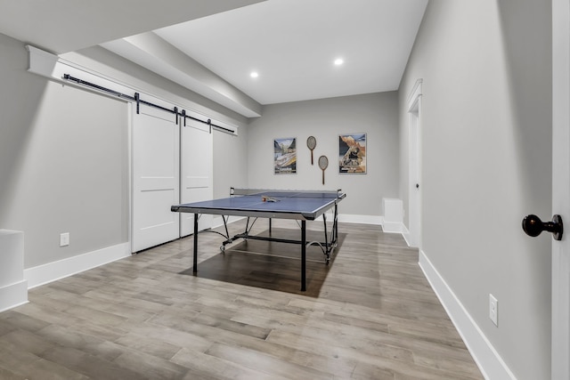 rec room with light wood-type flooring and a barn door