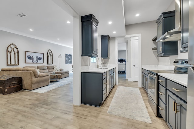 kitchen with light hardwood / wood-style flooring, wall chimney exhaust hood, stainless steel range with electric cooktop, and sink