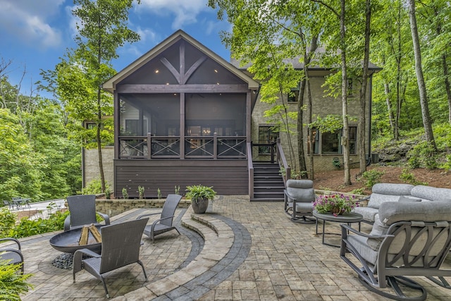 rear view of property featuring a fire pit, a patio area, and a sunroom