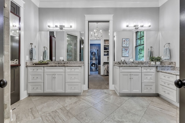 bathroom featuring vanity, stacked washing maching and dryer, and a chandelier