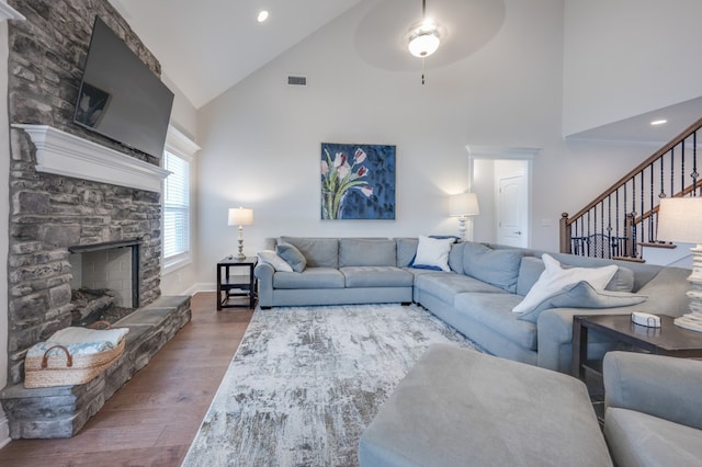 living room featuring ceiling fan, a fireplace, high vaulted ceiling, and wood-type flooring