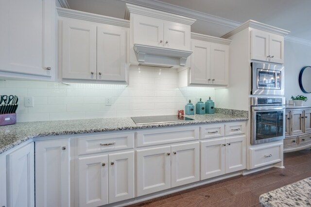 kitchen featuring appliances with stainless steel finishes, light stone counters, ornamental molding, dark wood-type flooring, and white cabinets