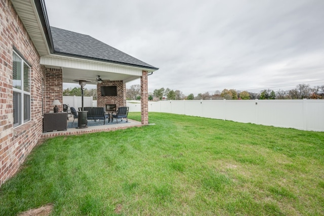 view of yard featuring an outdoor living space with a fireplace, ceiling fan, and a patio area