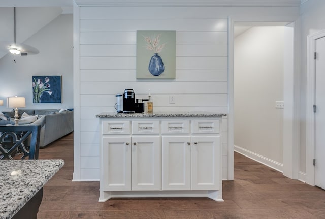 kitchen featuring white cabinets, light stone countertops, and dark wood-type flooring