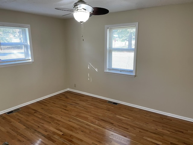 unfurnished room featuring plenty of natural light, dark wood-type flooring, and ceiling fan