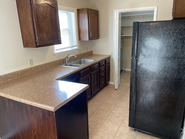 kitchen featuring dark brown cabinetry, sink, light tile patterned floors, and black appliances