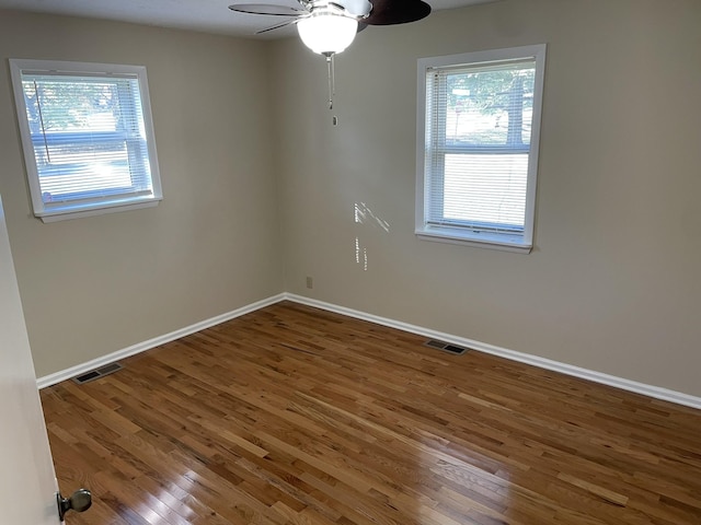 unfurnished room featuring dark hardwood / wood-style flooring, ceiling fan, and plenty of natural light