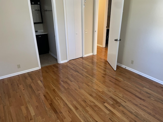 unfurnished bedroom with wood-type flooring and connected bathroom