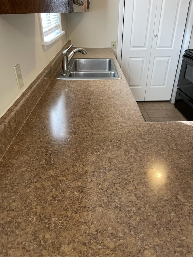 kitchen with light tile patterned floors, stove, and sink