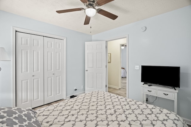 unfurnished bedroom featuring ceiling fan, a closet, light hardwood / wood-style floors, and a textured ceiling