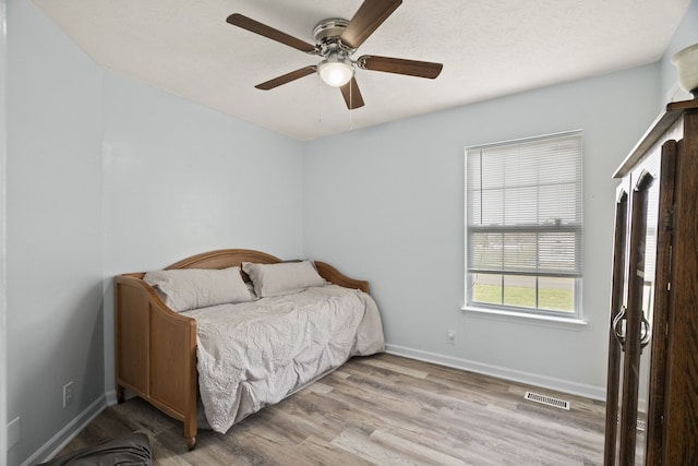 bedroom with ceiling fan, light hardwood / wood-style flooring, and a textured ceiling