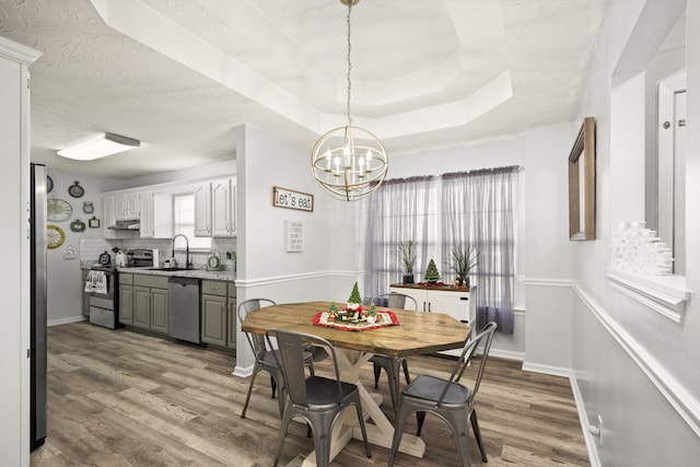 dining space with a chandelier, sink, light hardwood / wood-style floors, and a textured ceiling