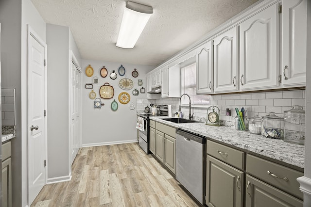 kitchen featuring sink, backsplash, a textured ceiling, appliances with stainless steel finishes, and light wood-type flooring