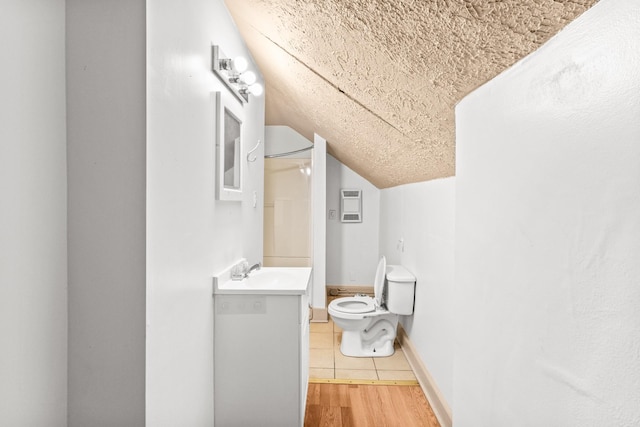 bathroom with toilet, wood-type flooring, vanity, and vaulted ceiling