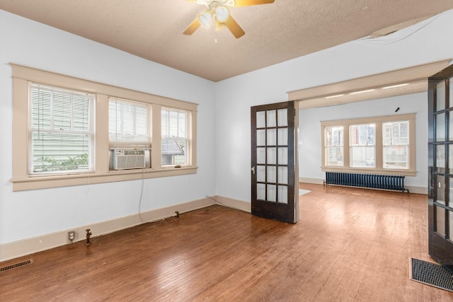 spare room featuring a wealth of natural light, radiator heating unit, and french doors