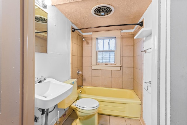 full bathroom with sink, tile patterned floors, a textured ceiling, toilet, and tiled shower / bath