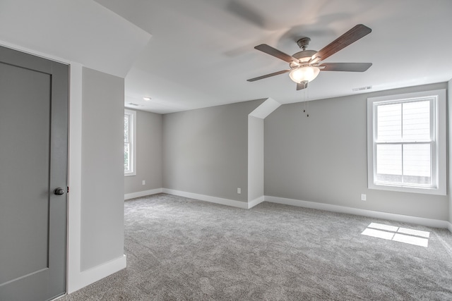 bonus room featuring plenty of natural light, ceiling fan, and light carpet